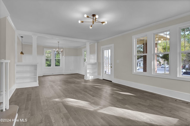 unfurnished living room featuring a chandelier, dark hardwood / wood-style flooring, a healthy amount of sunlight, and ornamental molding