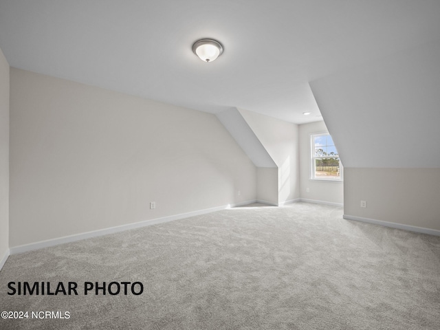 bonus room with light colored carpet and vaulted ceiling