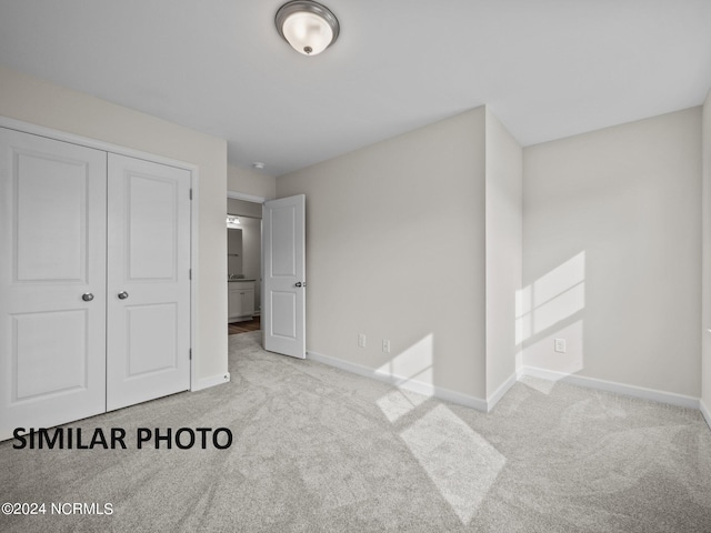 unfurnished bedroom featuring light carpet and a closet