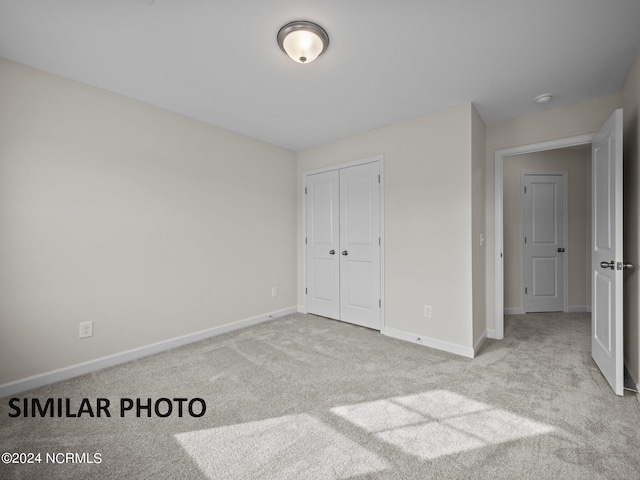 unfurnished bedroom with light colored carpet and a closet