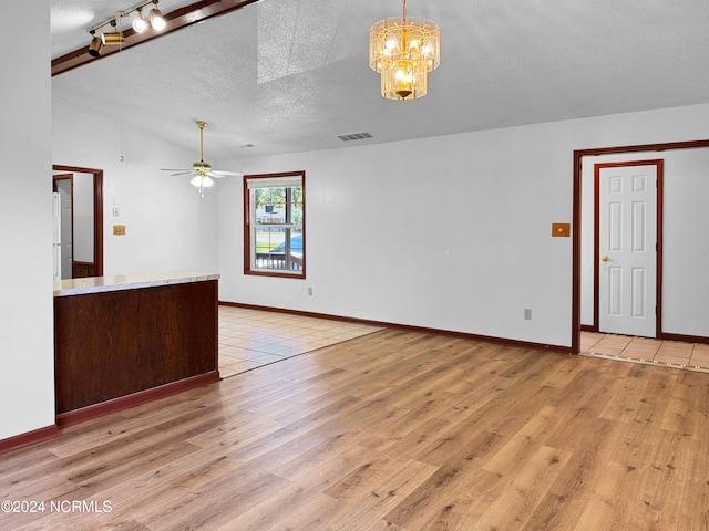 unfurnished living room with ceiling fan with notable chandelier, a textured ceiling, and light wood-type flooring