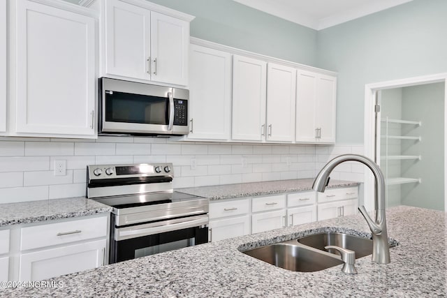 kitchen featuring backsplash, sink, appliances with stainless steel finishes, and white cabinets