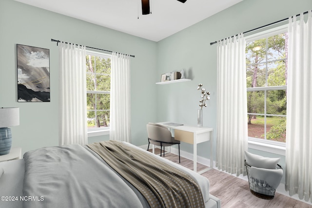 bedroom featuring multiple windows, light hardwood / wood-style floors, and ceiling fan