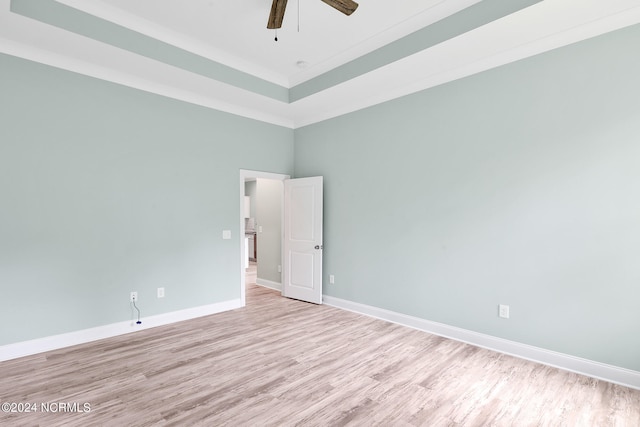 spare room with light hardwood / wood-style floors, crown molding, a towering ceiling, and ceiling fan