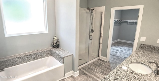 bathroom featuring vanity, wood-type flooring, and plus walk in shower