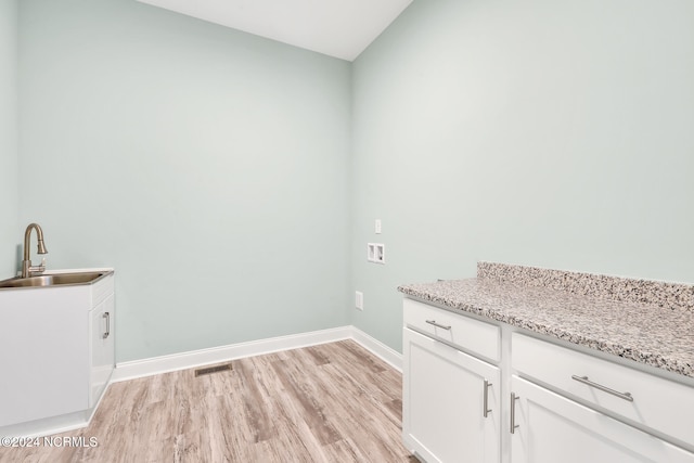 laundry room with hookup for a washing machine, light hardwood / wood-style flooring, cabinets, and sink