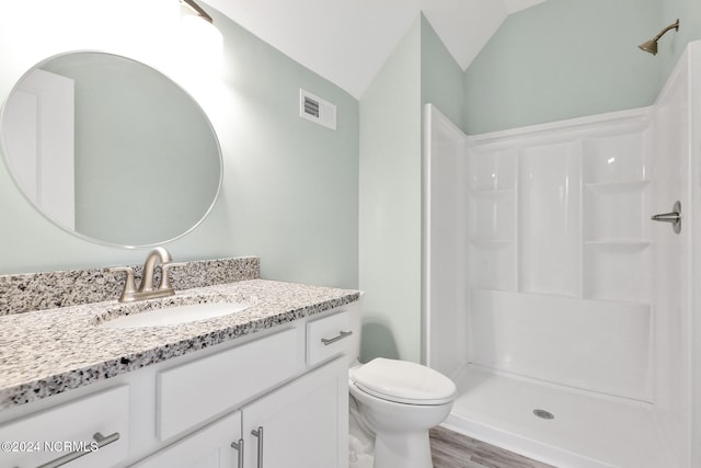 bathroom featuring hardwood / wood-style floors, walk in shower, vaulted ceiling, toilet, and vanity