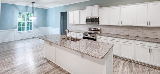 kitchen with tasteful backsplash, appliances with stainless steel finishes, sink, hanging light fixtures, and white cabinetry