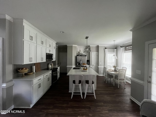 kitchen featuring white cabinets, an island with sink, appliances with stainless steel finishes, ornamental molding, and pendant lighting