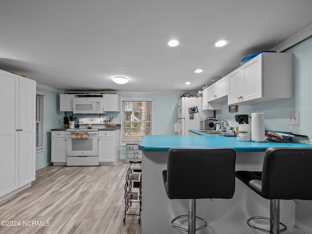 kitchen featuring a breakfast bar area, white cabinetry, light hardwood / wood-style flooring, sink, and white appliances