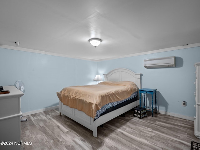 bedroom featuring ornamental molding, hardwood / wood-style floors, and a wall mounted AC