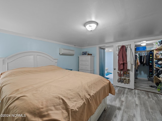 bedroom with hardwood / wood-style floors, crown molding, a wall mounted air conditioner, and a closet