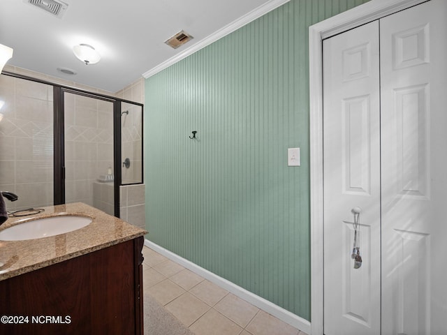 bathroom featuring vanity, ornamental molding, tile patterned flooring, and a shower with door