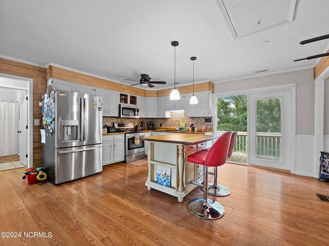 kitchen with wooden counters, light hardwood / wood-style flooring, hanging light fixtures, white cabinetry, and appliances with stainless steel finishes