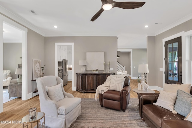 living room with crown molding, light wood-type flooring, and ceiling fan