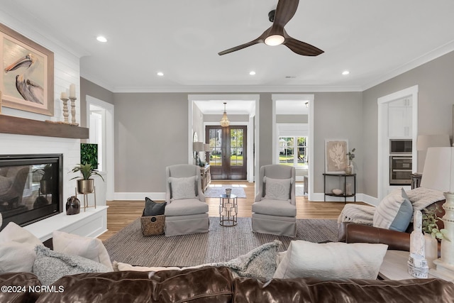 living room with crown molding, a fireplace, wood-type flooring, and ceiling fan