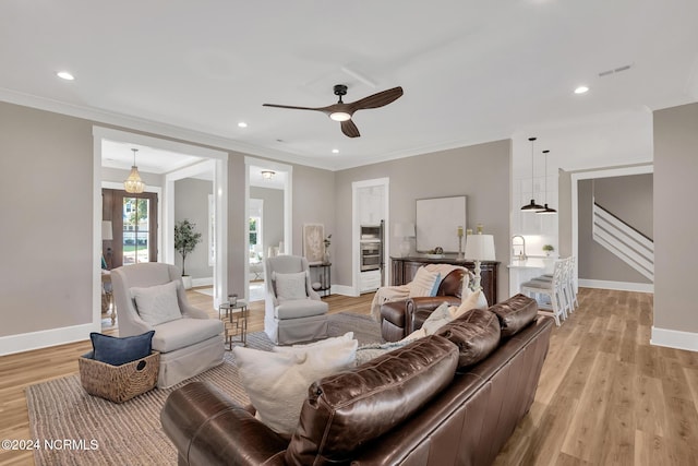 living room with light hardwood / wood-style floors, ornamental molding, sink, and ceiling fan