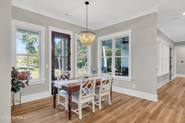 dining room with a notable chandelier, ornamental molding, and light wood-type flooring