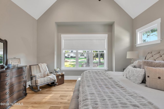 bedroom featuring high vaulted ceiling, multiple windows, and light hardwood / wood-style floors