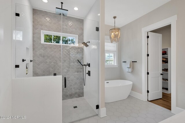 bathroom featuring independent shower and bath, a chandelier, and tile patterned flooring