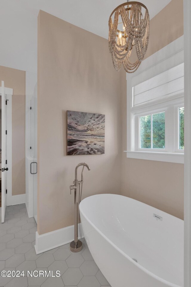 bathroom featuring plus walk in shower, an inviting chandelier, and tile patterned flooring