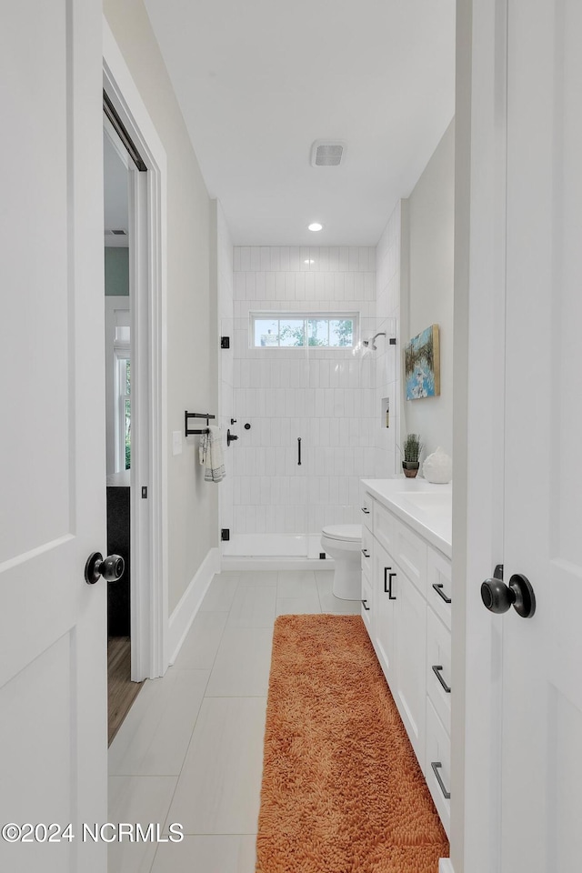 bathroom with vanity, a tile shower, toilet, and tile patterned floors