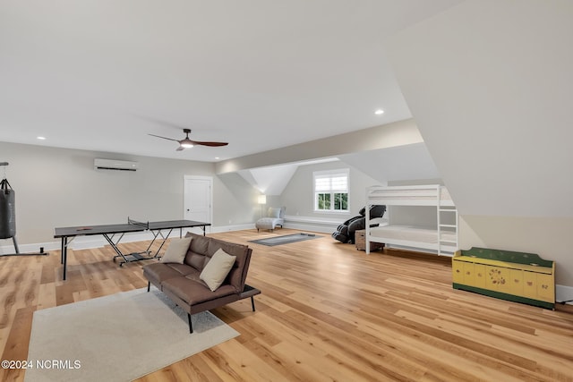 playroom featuring ceiling fan, an AC wall unit, and light hardwood / wood-style flooring