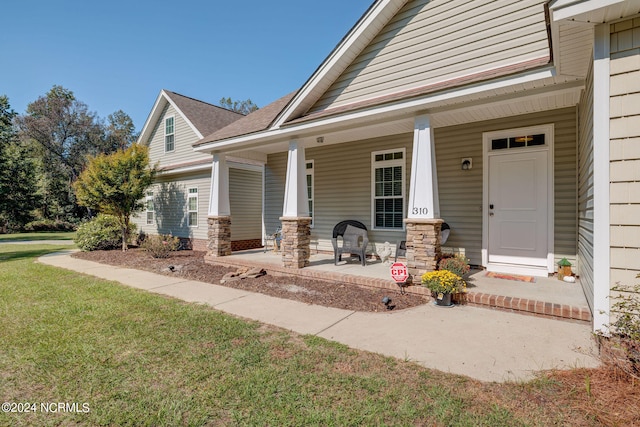 doorway to property with a yard and covered porch