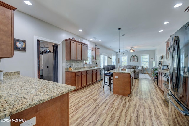 kitchen featuring decorative backsplash, fridge, light hardwood / wood-style flooring, hanging light fixtures, and a kitchen bar