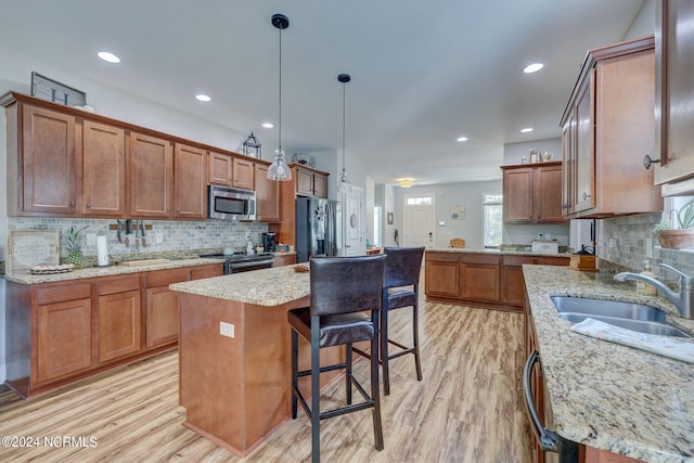 kitchen featuring hanging light fixtures, sink, a center island, appliances with stainless steel finishes, and light hardwood / wood-style floors