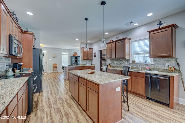 kitchen featuring stainless steel appliances, a center island, pendant lighting, light wood-type flooring, and tasteful backsplash