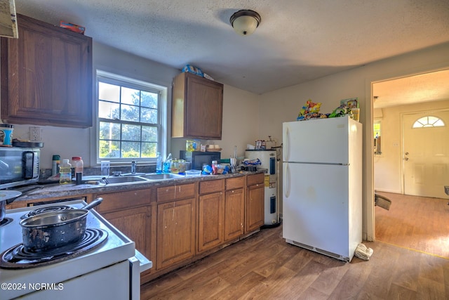 701 Anne St, Laurinburg, NC 28352 - kitchen with white appliances, a sink, brown cabinetry, and wood finished floors