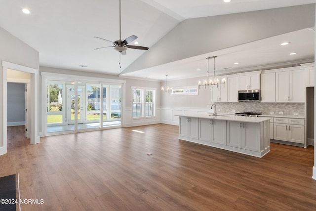 kitchen featuring hardwood / wood-style floors, white cabinetry, a kitchen island with sink, ceiling fan with notable chandelier, and decorative light fixtures