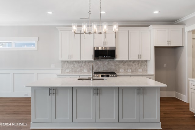 kitchen with dark wood-type flooring, decorative light fixtures, stainless steel appliances, and a center island with sink