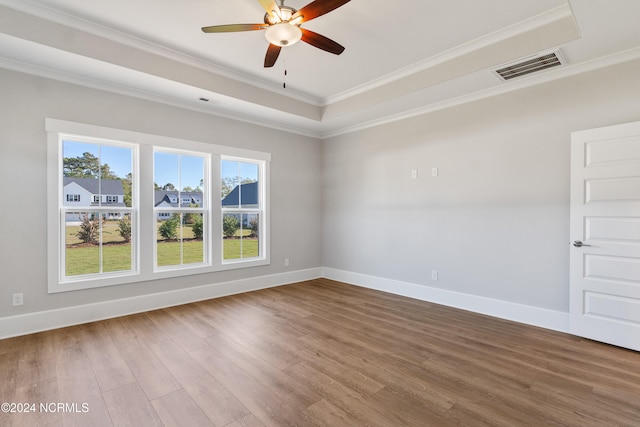 empty room with crown molding, a raised ceiling, wood-type flooring, and ceiling fan