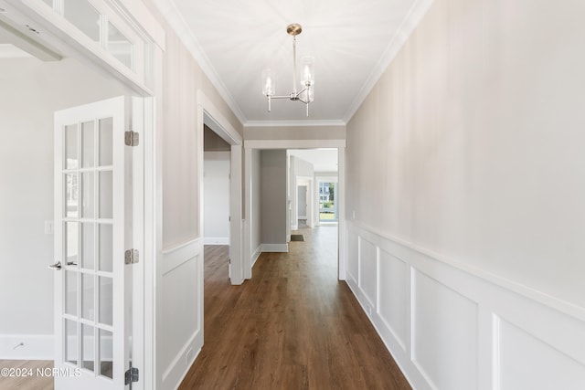 corridor with ornamental molding, dark hardwood / wood-style flooring, and a chandelier