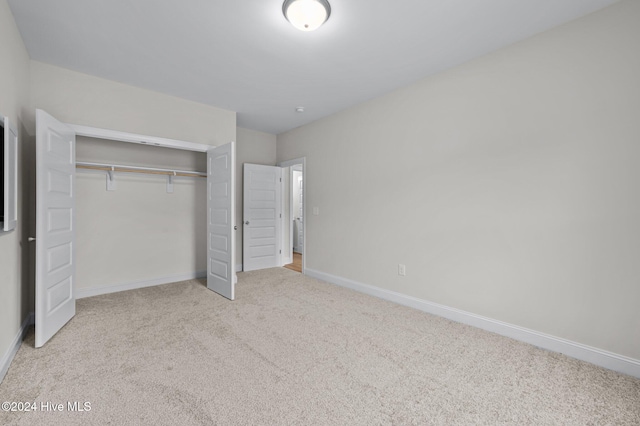 unfurnished bedroom featuring light colored carpet and a closet