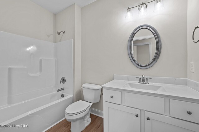 full bathroom featuring hardwood / wood-style flooring, vanity, toilet, and washtub / shower combination