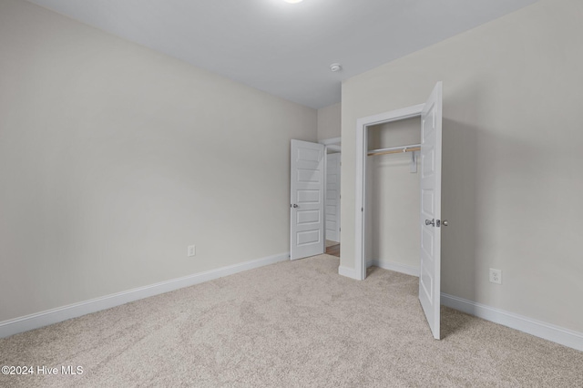 unfurnished bedroom with light carpet and a closet