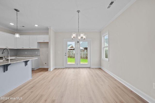 kitchen featuring white cabinetry, light stone countertops, tasteful backsplash, a chandelier, and a kitchen bar