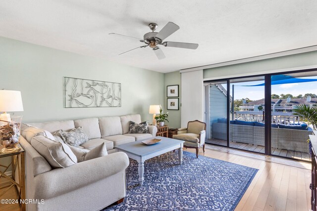 living room with a textured ceiling, ceiling fan, and light hardwood / wood-style flooring