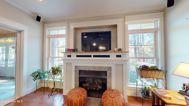 living room with ornamental molding, a tiled fireplace, and a wealth of natural light