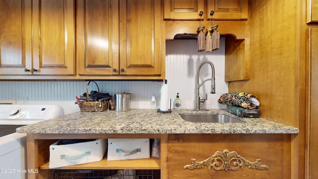 kitchen with light stone counters, sink, and washer / dryer