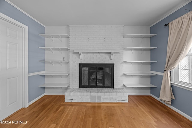 unfurnished living room with ornamental molding, a brick fireplace, and hardwood / wood-style floors