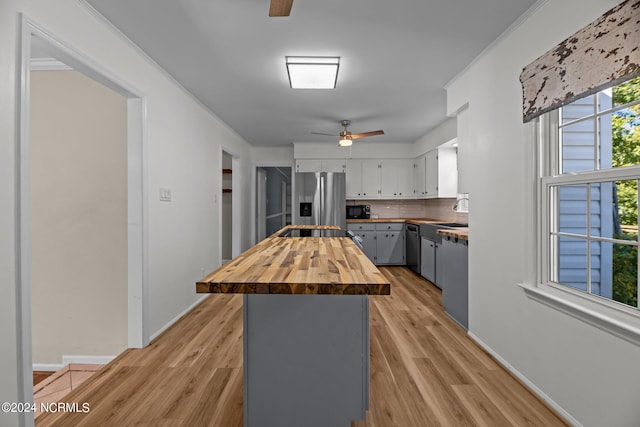 kitchen with gray cabinets, wood counters, appliances with stainless steel finishes, and light hardwood / wood-style floors