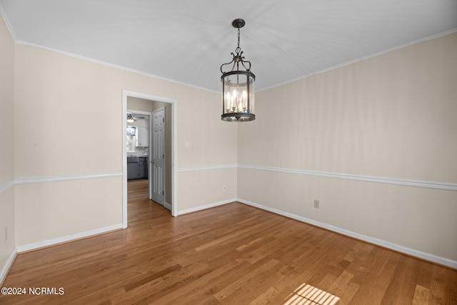 unfurnished dining area featuring hardwood / wood-style floors, a notable chandelier, and crown molding