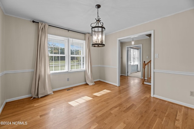 unfurnished dining area featuring ornamental molding, light hardwood / wood-style flooring, and an inviting chandelier