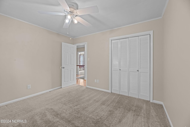 unfurnished bedroom with crown molding, carpet floors, a closet, and ceiling fan