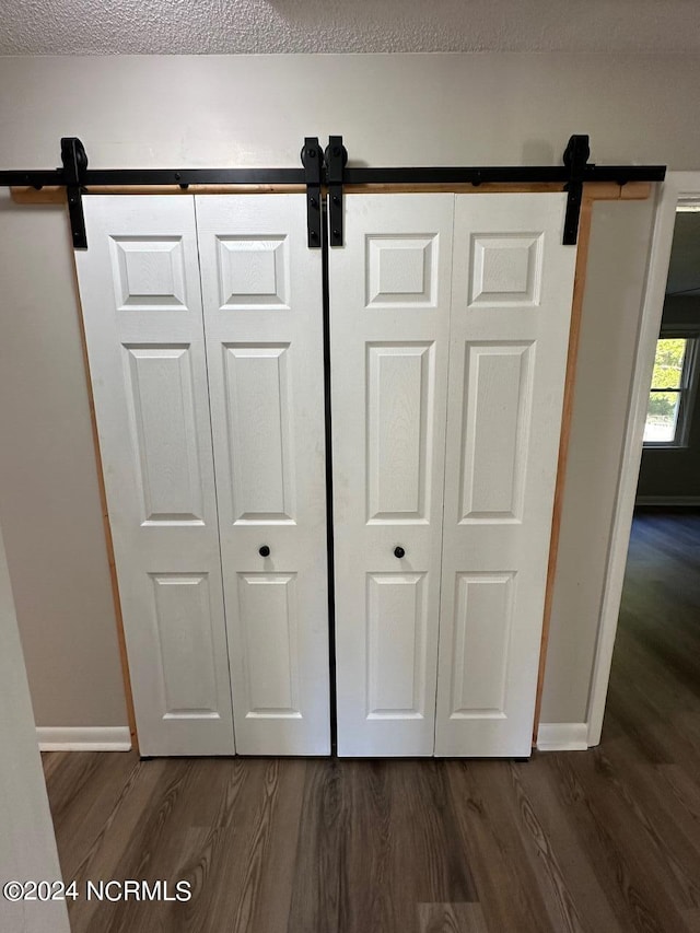 room details featuring a textured ceiling, a barn door, and wood-type flooring