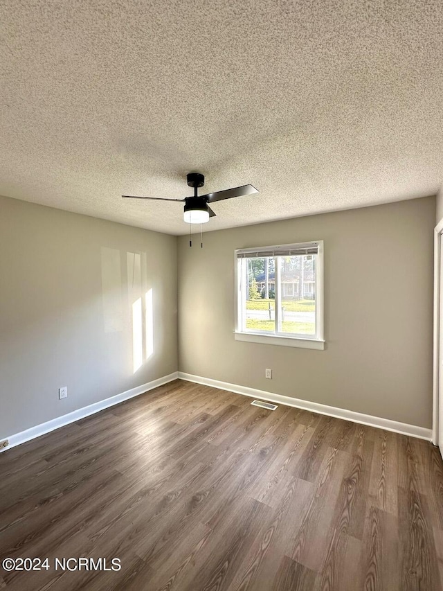 empty room with a textured ceiling, wood-type flooring, and ceiling fan